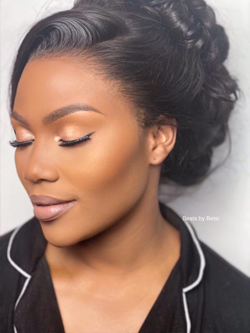 Soft glam makeup with a sleek updo, eyes closed